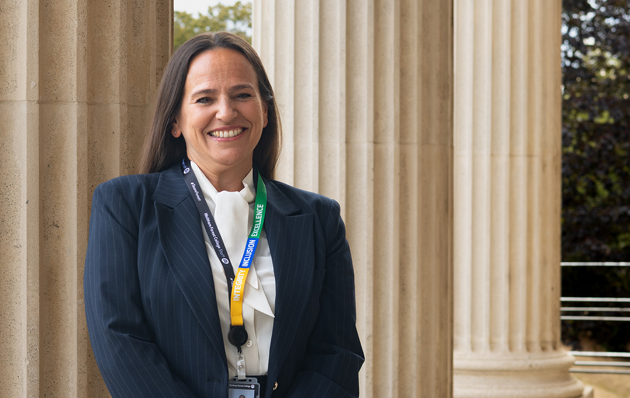 Principal Jane Button stands against stone pillars