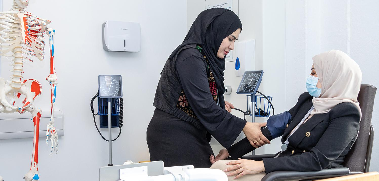 man on a walking frame being guided by student